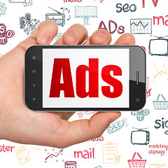 Image showing Advertising concept: Hand Holding Smartphone with Ads on display