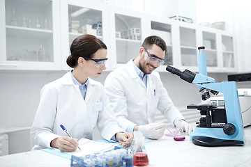 Image showing scientists with clipboard and microscope in lab