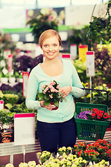 Image showing happy woman with shopping basket choosing flowers