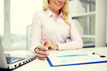 Image showing smiling businesswoman reading papers in office