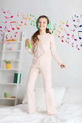 Image showing girl jumping on bed with smartphone and headphones