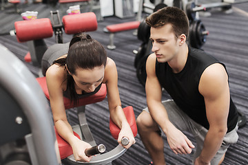 Image showing young woman with trainer exercising on gym machine