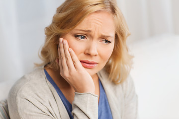 Image showing unhappy woman suffering toothache at home