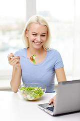 Image showing smiling woman with laptop eating salad at home