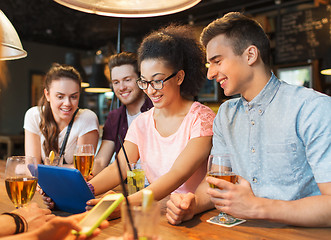 Image showing happy friends with tablet pc and drinks at bar