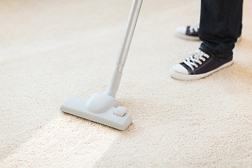 Image showing close up of male hoovering carpet