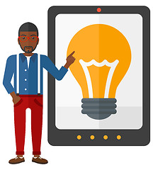 Image showing Man pointing at tablet computer with light bulb on screen.