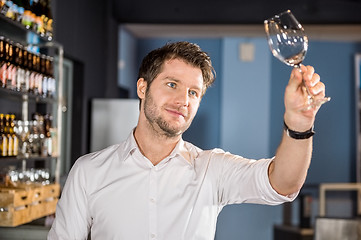 Image showing Bartender Examining Glass Of Wine In Bar