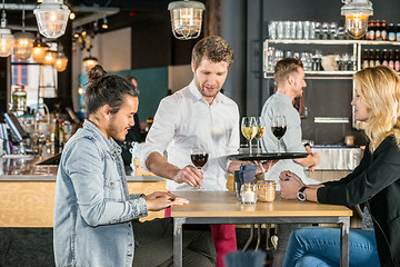 Image showing Waiter Serving Wine To Customers In Bar