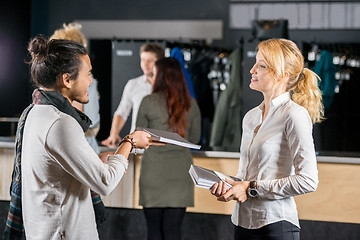 Image showing Man Giving Book To Friend By Bag Deposit Counter