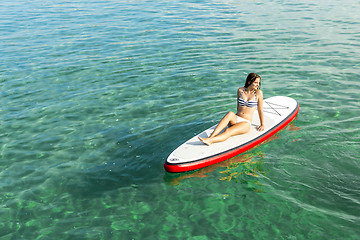 Image showing Woman relaxing over a paddle surfboard