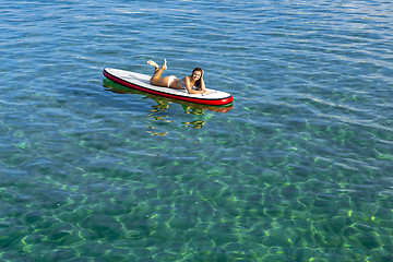 Image showing Woman relaxing over a paddle surfboard