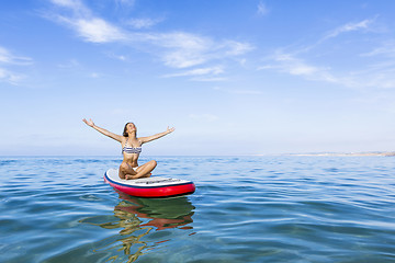 Image showing Woman relaxing over a paddle surfboard