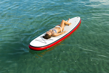 Image showing Woman relaxing over a paddle surfboard