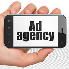 Image showing Marketing concept: Hand Holding Smartphone with Ad Agency on display