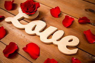 Image showing close up of word love cutout with red rose on wood