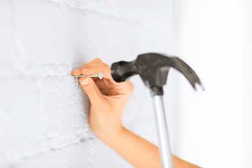 Image showing architect hammering nail in wall