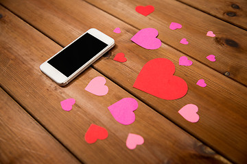 Image showing close up of smartphone and hearts on wood