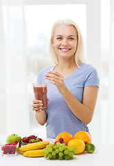 Image showing smiling woman drinking fruit shake at home