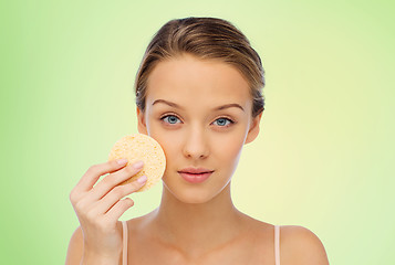 Image showing young woman cleaning face with exfoliating sponge