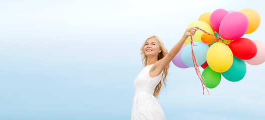 Image showing smiling woman with colorful balloons outside