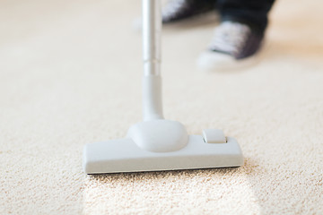 Image showing close up of male hoovering carpet