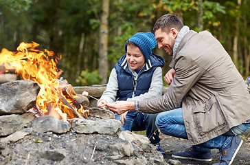 Image showing father and son roasting marshmallow over campfire