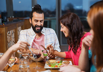 Image showing friends eating and tasting food at restaurant