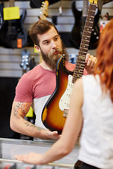 Image showing assistant showing customer guitar at music store