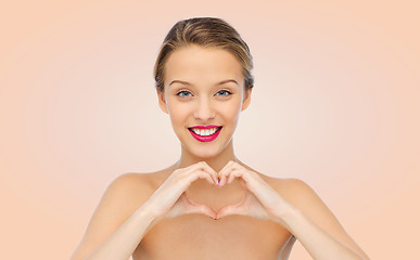 Image showing smiling young woman showing heart shape hand sign