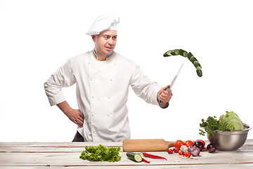 Image showing Chef cutting a green cucumber in his kitchen