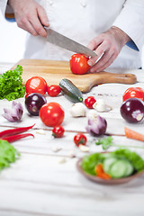 Image showing Chef cutting a red tomato his kitchen