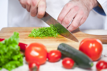 Image showing Chef cutting a green lettuce his kitchen