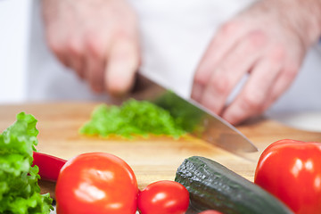 Image showing Chef cutting a green lettuce his kitchen