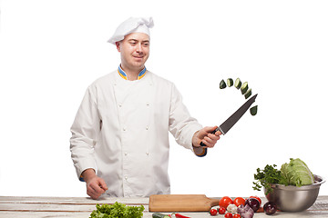 Image showing Chef cutting a green cucumber in his kitchen