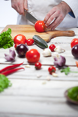 Image showing Chef cutting a red tomato his kitchen