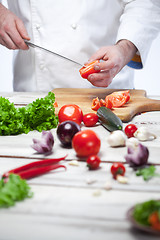 Image showing Chef cutting a red tomato his kitchen