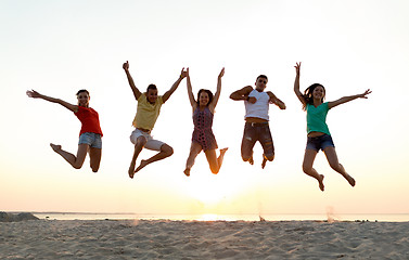 Image showing smiling friends dancing and jumping on beach