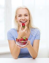 Image showing happy woman eating strawberry at home