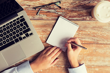 Image showing close up of female hands with laptop and notebook