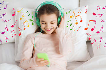 Image showing happy girl lying in bed with smartphone at home