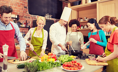 Image showing happy friends and chef cook cooking in kitchen