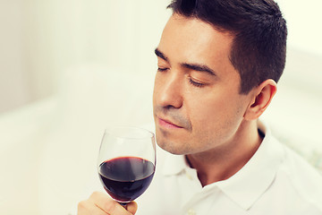 Image showing happy man drinking red wine from glass at home