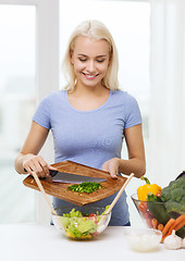 Image showing smiling woman cooking vegetable salad at home