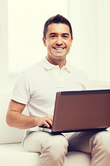 Image showing happy man working with laptop computer at home