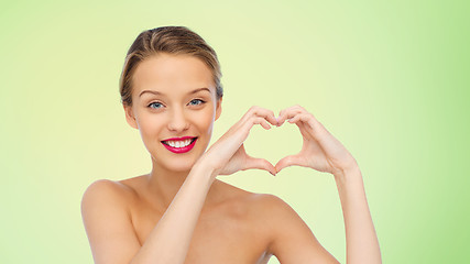 Image showing smiling young woman showing heart shape hand sign