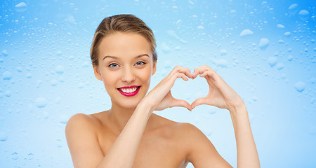 Image showing smiling young woman showing heart shape hand sign