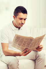 Image showing sad man reading newspaper at home