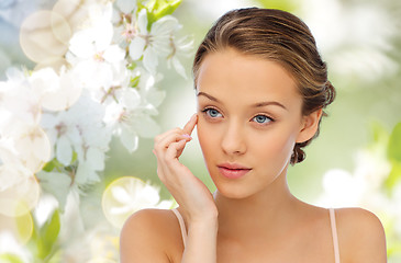 Image showing young woman applying cream to her face