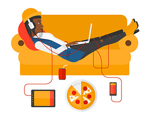 Image showing Woman with gadgets lying on sofa.